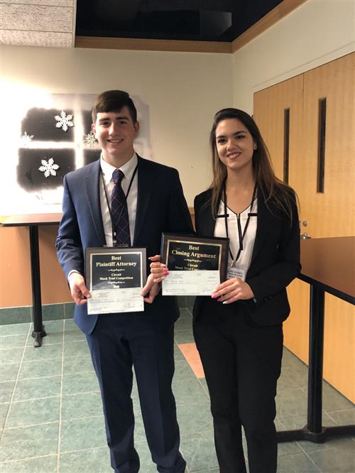 two students posing with awards 